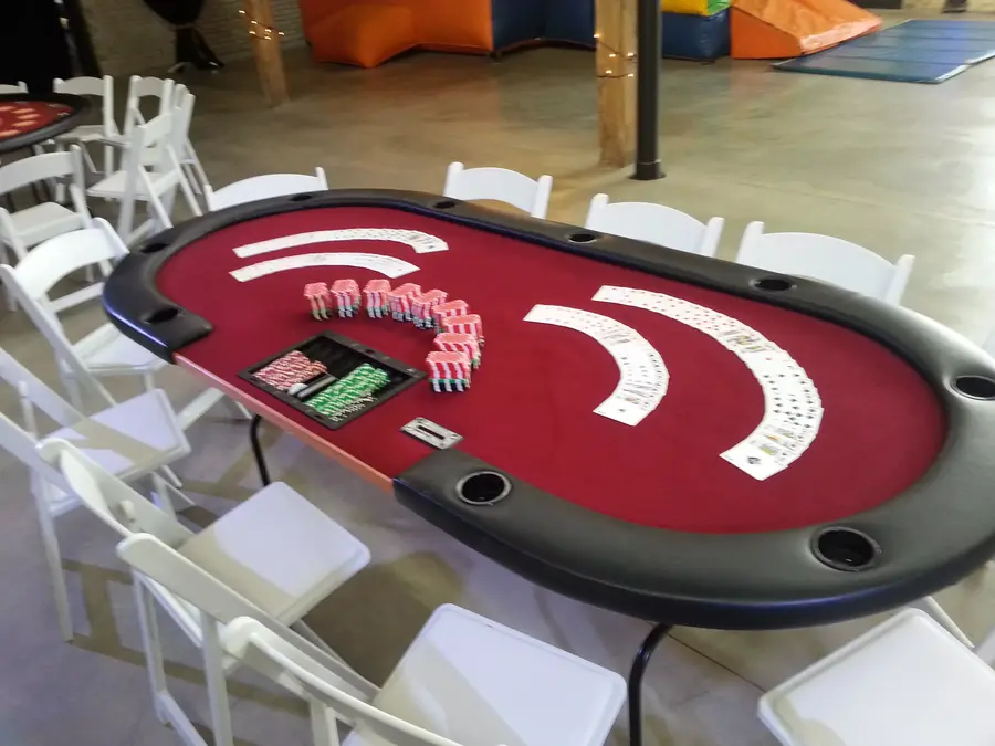 A red felt poker table arranged with cards and chips at an event venue.